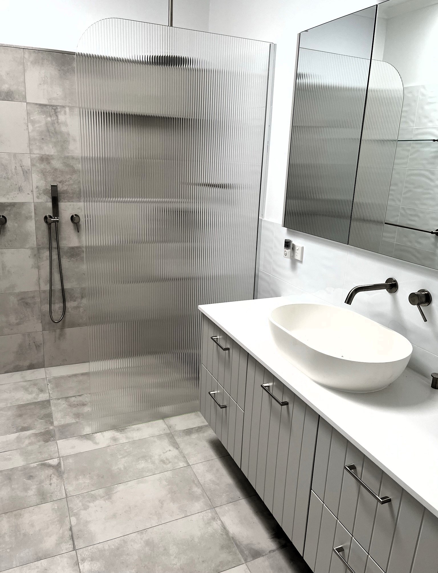 Bathroom with a grey fluted vanity, vessel basin and fluted glass shower screen