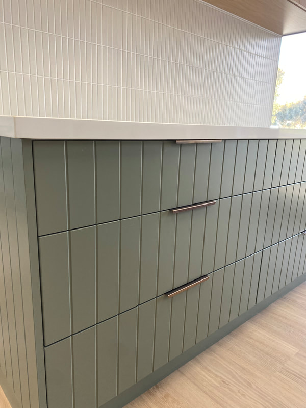 Sage green V groove cabinetry with brass handles
