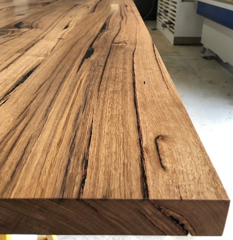 Close up of a solid timber bench top with a filled natural crack