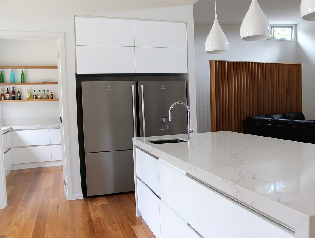 White handleless kitchen with a timber batten feature panel